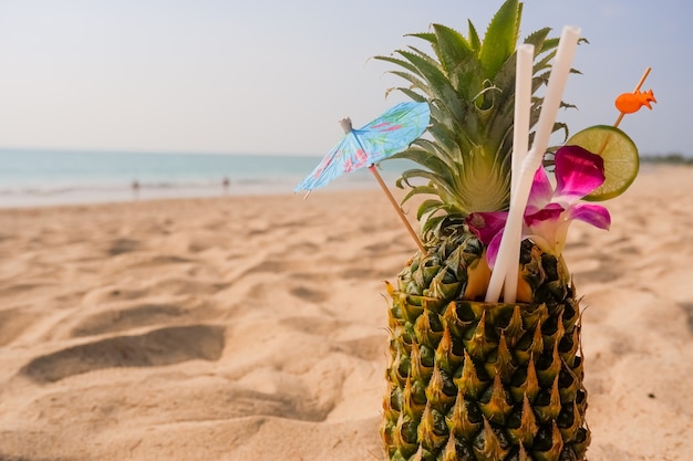 Cóctel de piña tropical Piña fresca tumbada en el fondo de la playa de arena