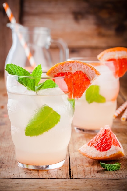 Cóctel de pomelo frío con menta en vaso sobre mesa de madera