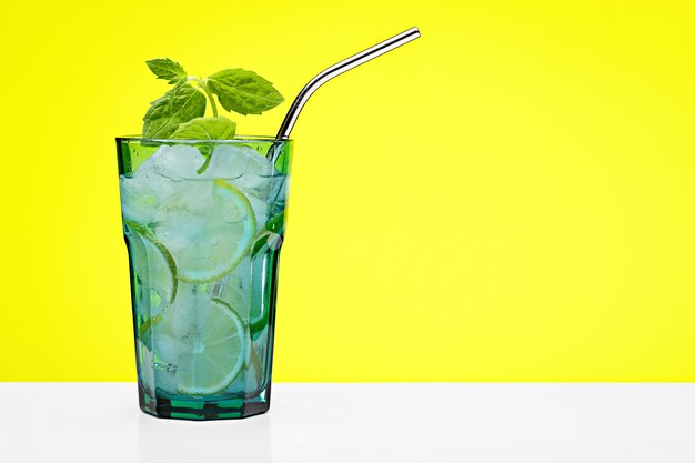 Cóctel refrescante con cítricos y una ramita de menta en un gran vaso azul