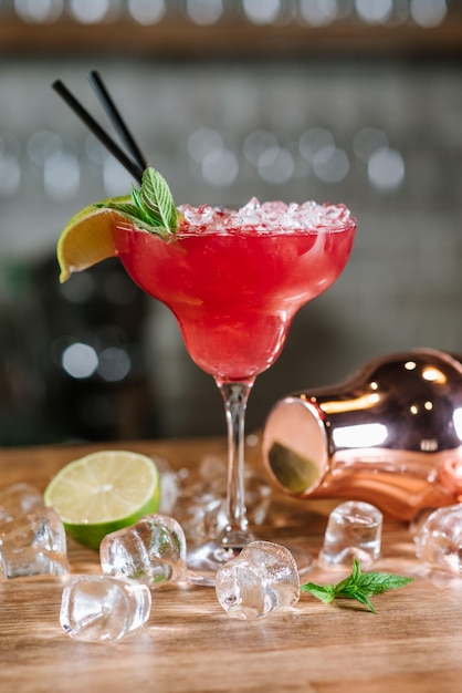 Un cóctel rojo con hielo picado en vaso en el fondo del bar