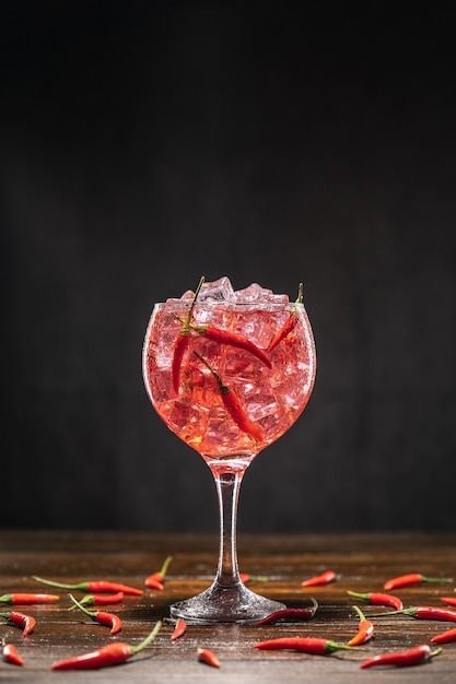 Cóctel rojo en un vaso con hielo y chiles