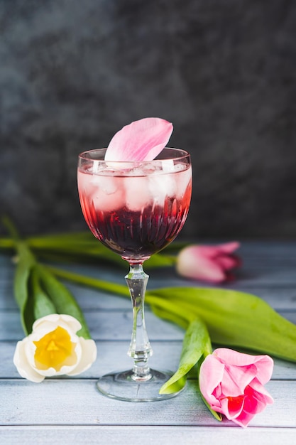 Cóctel rosa con champán o prosecco y hielo en copa de vino de cristal y tulipanes blancos y blancos