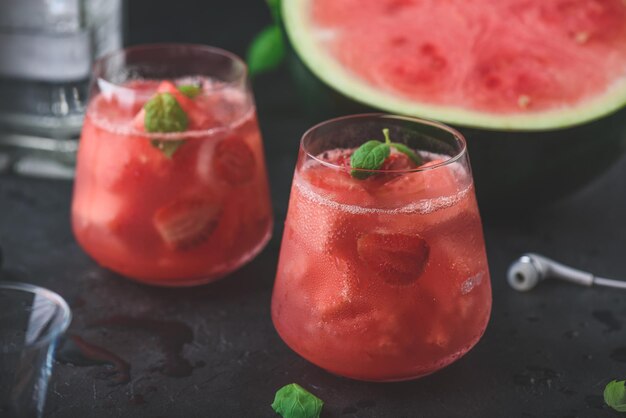 Coctel de sandía y fresa con guarnición de menta sobre un fondo de hormigón oscuro