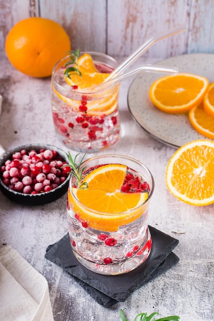 Cóctel de seltzer duro con bayas, naranja, romero y hielo en vasos sobre la mesa Vista vertical