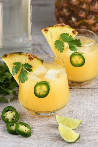 Cóctel de tequila con jugo de piña, rodajas de jalapeño y cilantro, enfriado con hielo