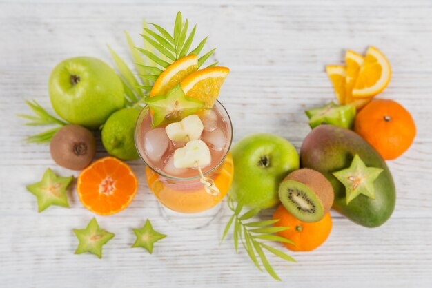 Cóctel de verano con varias frutas tropicales alrededor.