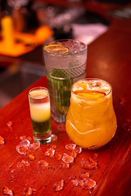 Foto cócteles fríos con limón y menta y hielo en un vaso con gotas de bebida alcohólica en el bar