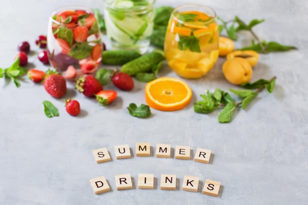 Foto cócteles de frutas frescas de verano conjunto de bebidas de verano sobre fondo de hormigón gris mocktails con fresa cereza pepino albahaca albaricoque naranja y menta
