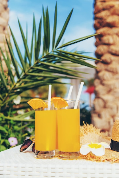 Cócteles, gafas de sol y frutas frescas en un cuenco blanco junto a la piscina