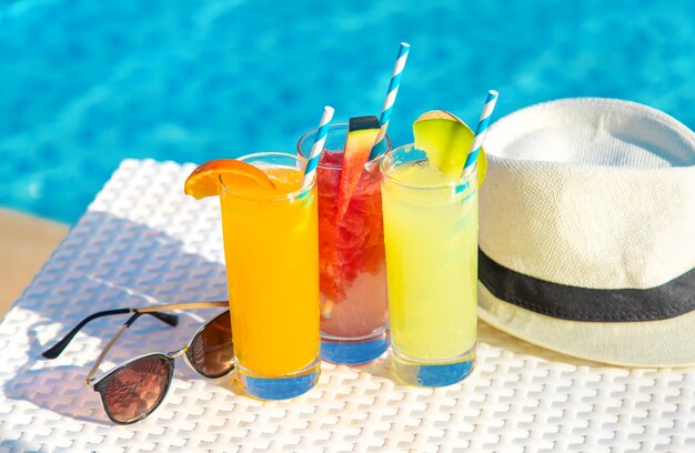 Cócteles, gorro y gafas de sol junto a la piscina.