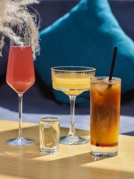 Cócteles en la mesa bebidas de diferentes colores en diferentes vasos en la mesa de madera oscura sobre desenfoque