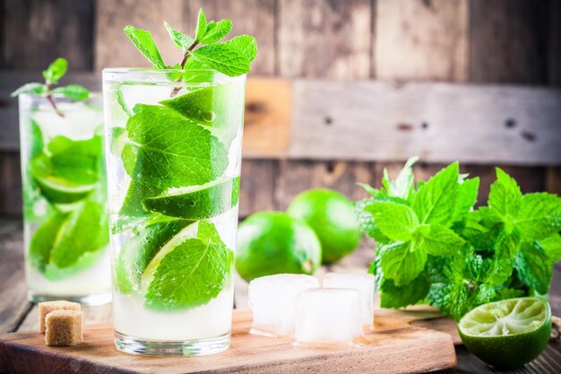 Cócteles de mojito fresco con menta lima y hielo en vidrio sobre fondo de madera