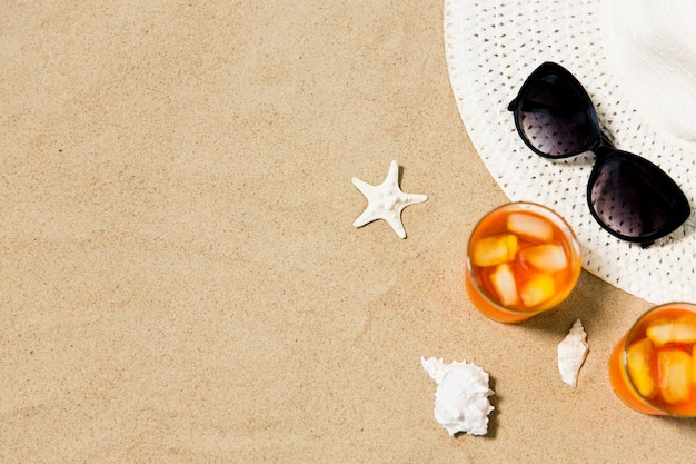 cócteles sombrero de sol y gafas de sol en la arena de la playa