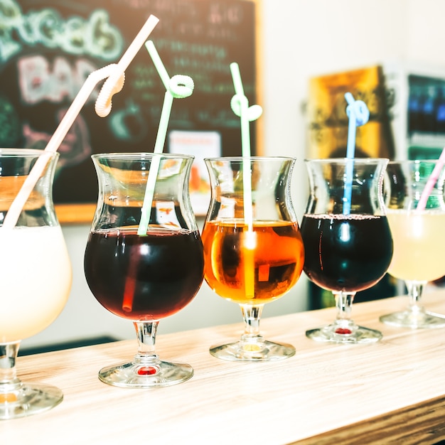 Cócteles de verano coloridos en vasos con pajitas. Bebidas de pie sobre la barra del bar. Vino, piña colada y zumo de manzana. Fresco y frío para el verano.