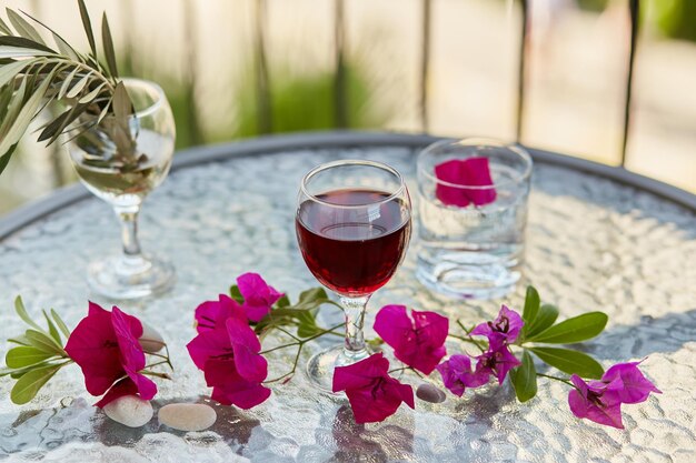 Cócteles de verano y una elegante copa de vino tinto Flores rosas decorativas y una rama de olivo