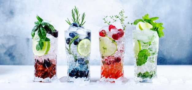 Cócteles de verano o cócteles sin alcohol y bebidas frías Bebida refrescante de mojito con arándanos, moras, frambuesas y hierbas de lima y hielo sobre fondo gris