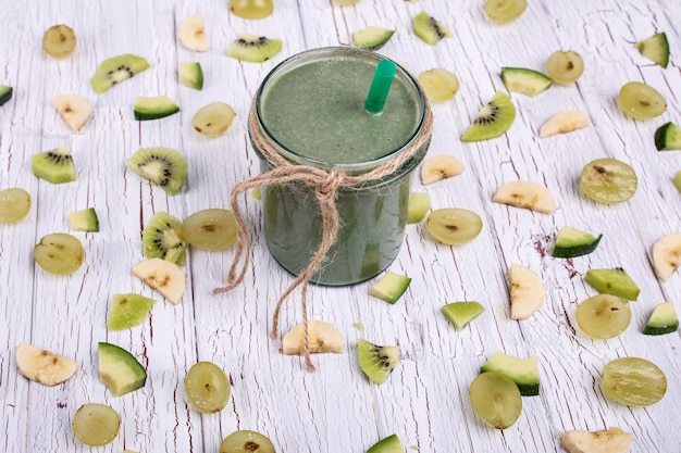 Foto cocto de desintoxicação verde está na mesa com pequenos pedaços de frutas e vegetais