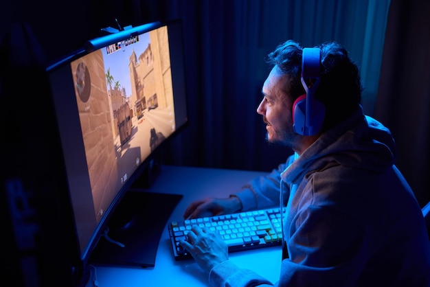 Un codificador está trabajando tarde en la noche en una pantalla de computadora codificando y usando una aplicación de teléfono inteligente