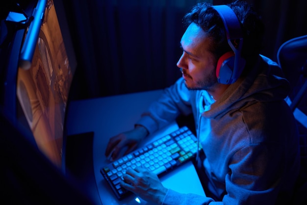 Un codificador está trabajando tarde en la noche en una pantalla de computadora codificando y usando una aplicación de teléfono inteligente