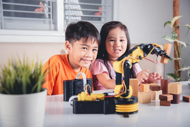 Código de programa de niña pequeña para robot con computadora portátil y prueba de niño con control remoto para recoger bloques de madera