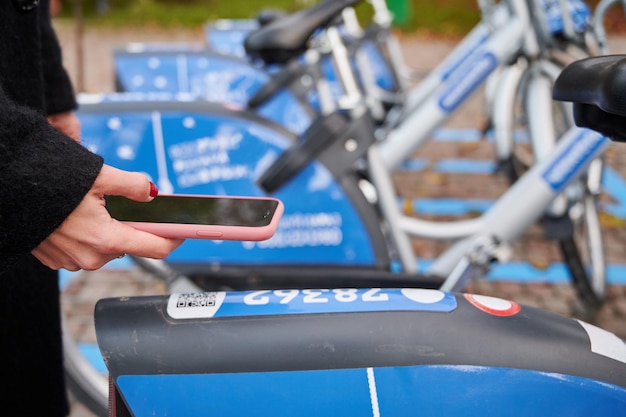 Código QR escaneado femenino por teléfono inteligente para alquilar una bicicleta