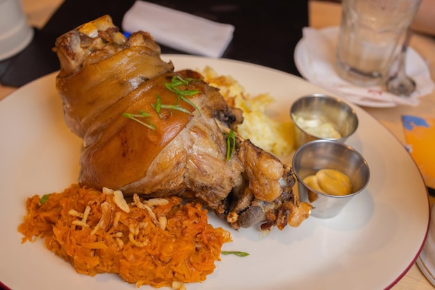 Codillo de cerdo asado eisbein con repollo hervido estofado y mostaza en tabla de cortar de madera