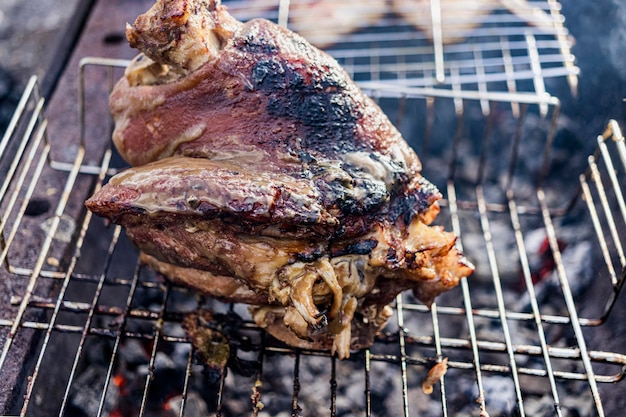 Codillo de cerdo jugoso a la parrilla. Codillo apetitoso o pezuña de jabalí. Cocinar la pierna de cerdo a las brasas. De cerca. Enfoque selectivo.