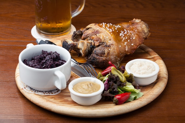 Codillo con guarnición y un vaso de cerveza