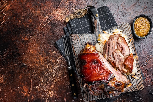 Codillo de jamón de cerdo asado Schweinshaxe con chucrut servido en una tabla de madera Fondo oscuro Vista superior Espacio de copia