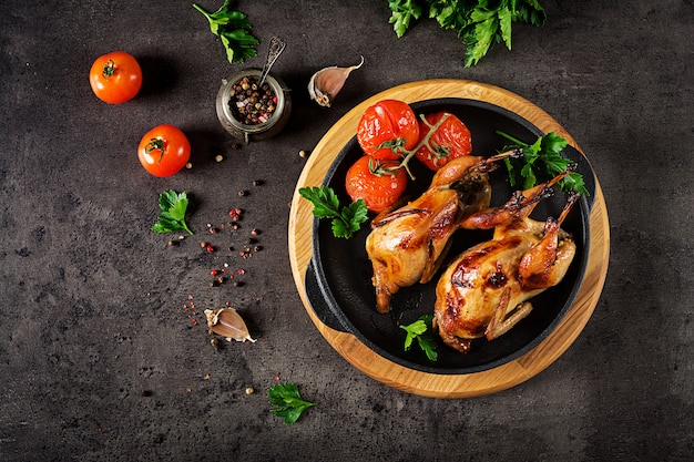 Codornices al horno en sartén sobre un fondo oscuro