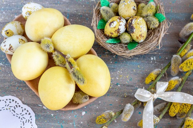 Codornices amarillas y huevos de gallina para Pascua en un plato de arcilla hecho a mano