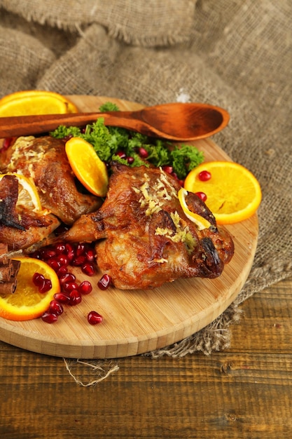 Codornices asadas en tabla de cortar sobre tela de saco sobre fondo de mesa de madera