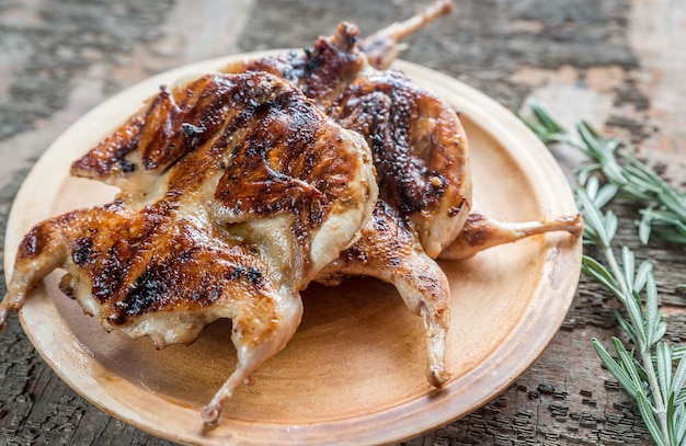 Codornices a la plancha en un plato sobre fondo rústico