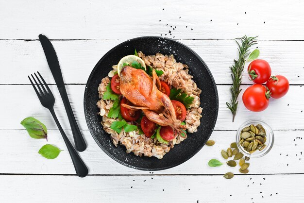 Codorniz al horno con avena y verduras Sobre un fondo blanco de madera Vista superior Espacio libre para el texto