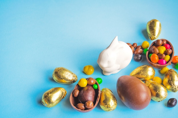 Coelhinho da Páscoa branco com ovos de chocolate embrulhado em papel dourado e doces em azul claro