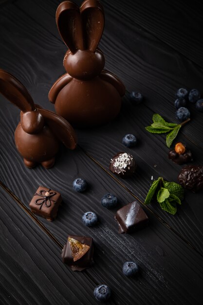 Coelhinho da páscoa de chocolate com doces em uma mesa de madeira escura