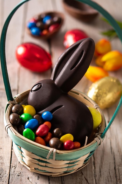 Coelhinho da Páscoa de chocolate e ovos coloridos na mesa de madeira