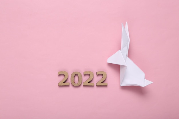 Coelhinho da páscoa de origami e 2022 em fundo rosa