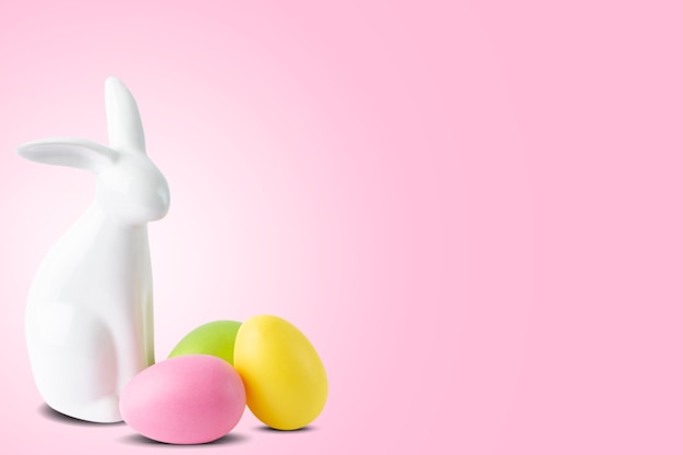 Coelhinho da Páscoa e ovos pintados coloridos sobre fundo rosa pastel moderno. Fundo festivo de primavera com lugar para texto, conceito de férias de Páscoa feliz.