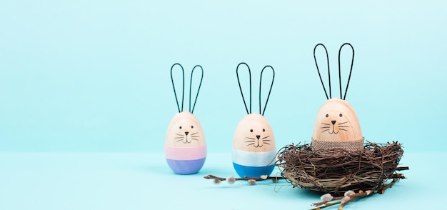 Foto coelhinho da páscoa ou grupo de coelhos com cesta de vime, ramos de salgueiro, ovo de madeira, saudação de férias de primavera