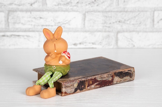 Coelho de brinquedo decorativo de cerâmica sentado em um livro antigo