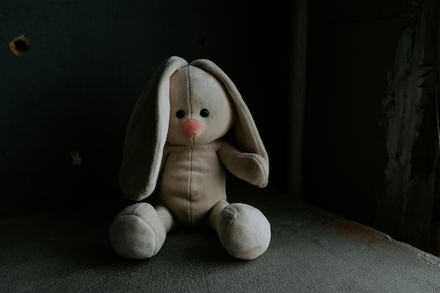 Coelho de brinquedo perdido está sentado sozinho em uma sala Morte de guerra e tema de infância perdida