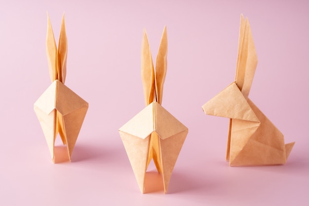 Coelho de papel origami em fundo rosa. Artesanato de papel. O conceito mínimo de Páscoa ou ano do coelho. Coelhinho da Páscoa.