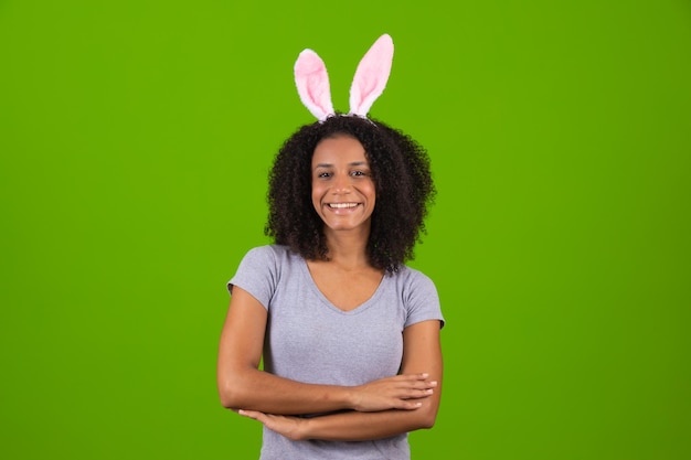 Coelho festivo e ovos temperados feliz mulher moderna em orelhas de coelhinho da Páscoa isoladas em fundo verde