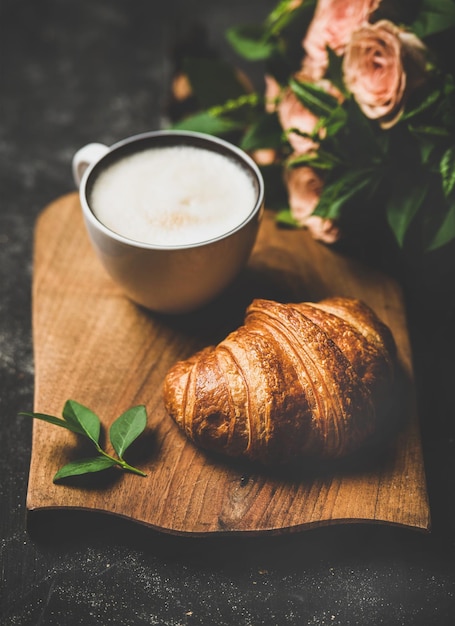 Coffee-break com croissants de cappuccino e flores de primavera rosa