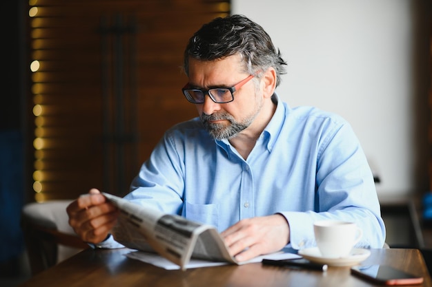 Coffee break hombre bebiendo café y leyendo el periódico en el café bar