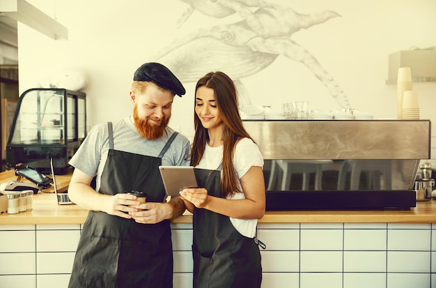 Coffee business concept baristas alegres olhando para seus tablets para pedidos online