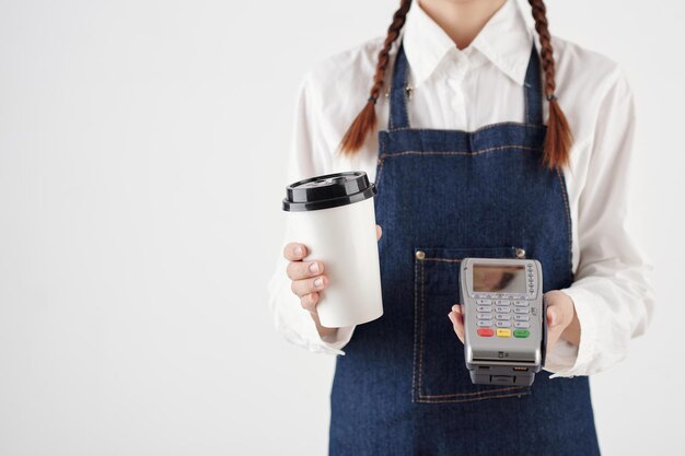 Coffeeshop barista sosteniendo una taza de café desechable y terminal de pago