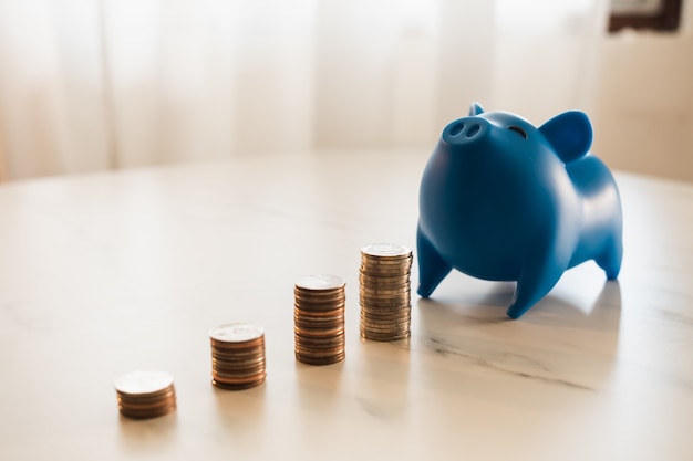 Foto cofrinho azul colocado em uma mesa com moedas espalhadas