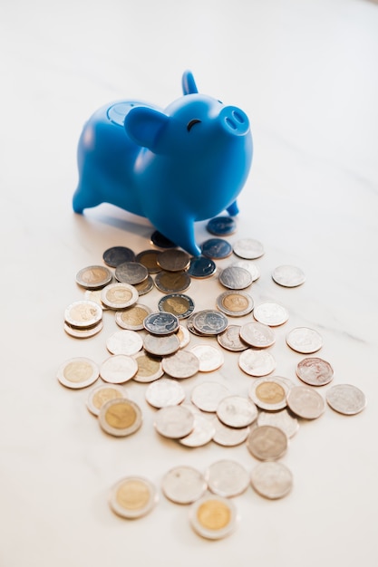 Foto cofrinho azul colocado em uma mesa com moedas espalhadas